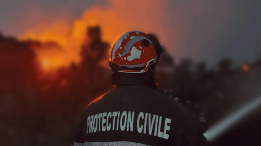 Un agent de la Protection civile, de dos, face aux flammes lors des incendies de Jijel.