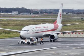 Avion d'Air Algérie remorqué sur le tarmac d'un aéroport, par temps pluvieux