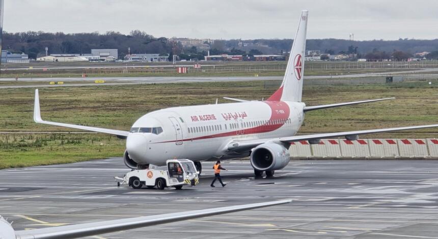 Avion d'Air Algérie remorqué sur le tarmac d'un aéroport, par temps pluvieux