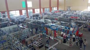 Vue en hauteur d’un hall du Salon international du livre d’Alger, avec ses allées de stands remplis de livres et des visiteurs qui circulent