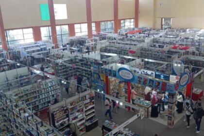 Vue en hauteur d’un hall du Salon international du livre d’Alger, avec ses allées de stands remplis de livres et des visiteurs qui circulent