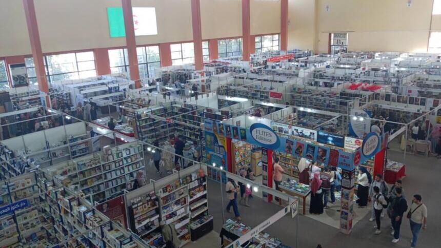 Vue en hauteur d’un hall du Salon international du livre d’Alger, avec ses allées de stands remplis de livres et des visiteurs qui circulent