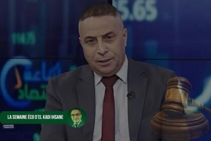 Djelloul Slama, en costume gris et cravate bordeaux, sur un plateau de télévision devant un fond de courbes boursières